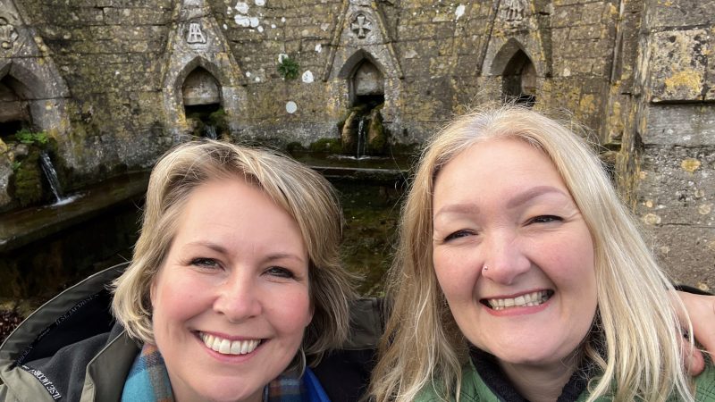 Rev Helen James and Kelly Peacey are smiling infront of the Seven Wells at Bisley